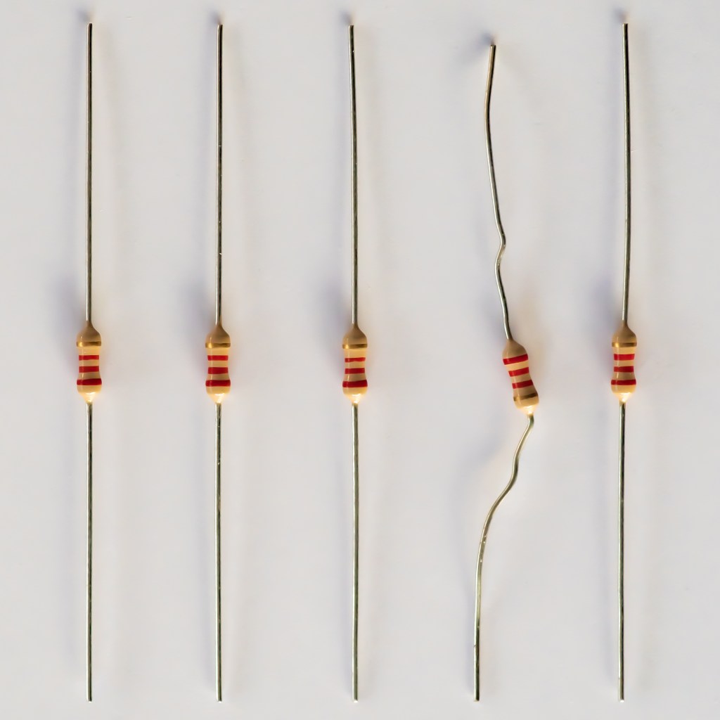 Close-up of 5 2.2KΩ (red-red-red-gold) resistors in a row; the fourth one is crooked, the other four are straight.