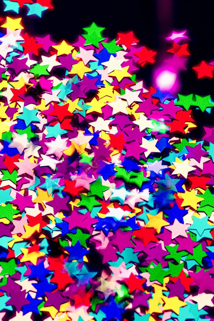 A bunch of colorful star confetti, with a few still landing in the mass that's already set.
