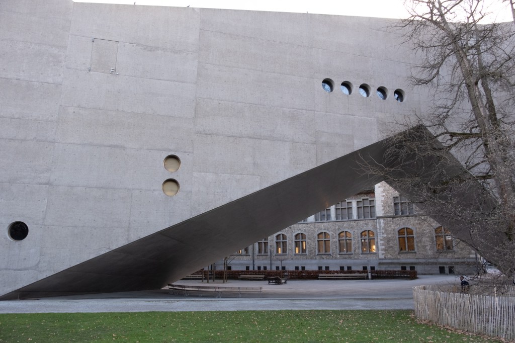 A triangle in a concrete building showing a much older building behind it