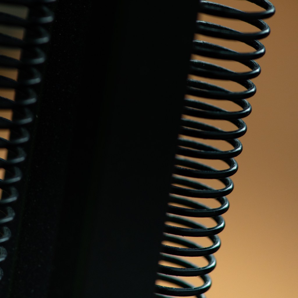 A black center axle with two springs on its side over a light brown background.