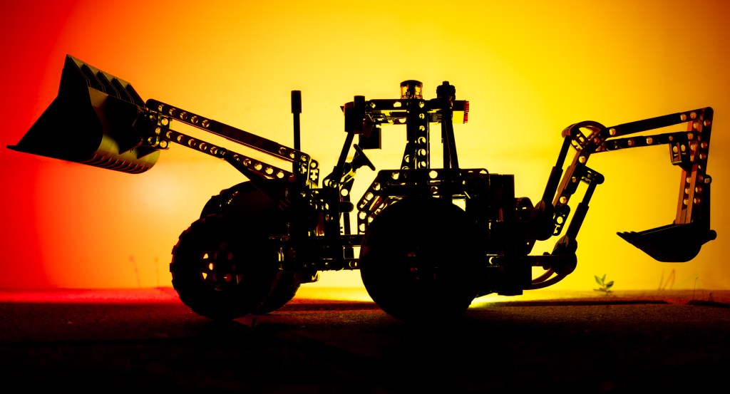 A LEGO tractor silhouette against a red/yellow background reminiscent of a sunset