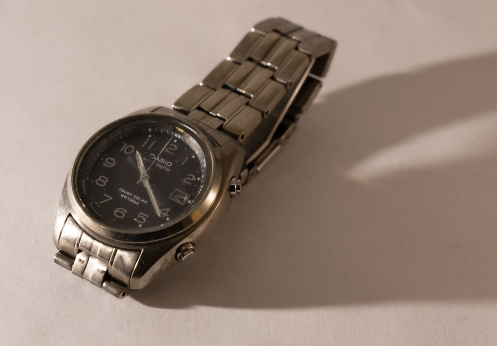 A Casio watch on a white background, showing a long shadow on its right.