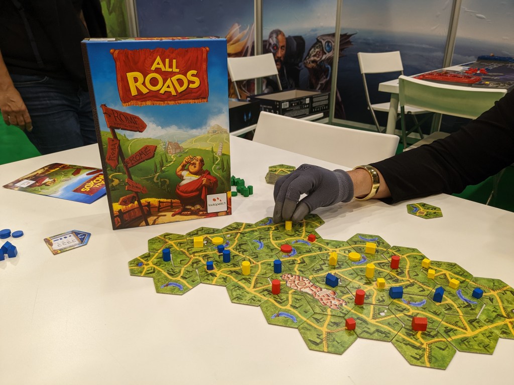 All roads - a board made of hexagonal tiles that all have roads on them; cubes, houses and cylinders of players colors are on the board.