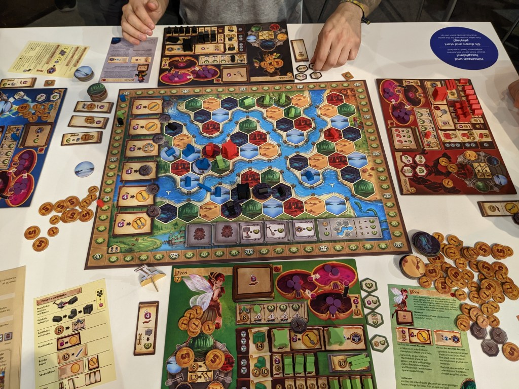 Terra Nova - a hex board looking like a Terra Mystica map with various terrains, and different faction player boards with houses and gold.