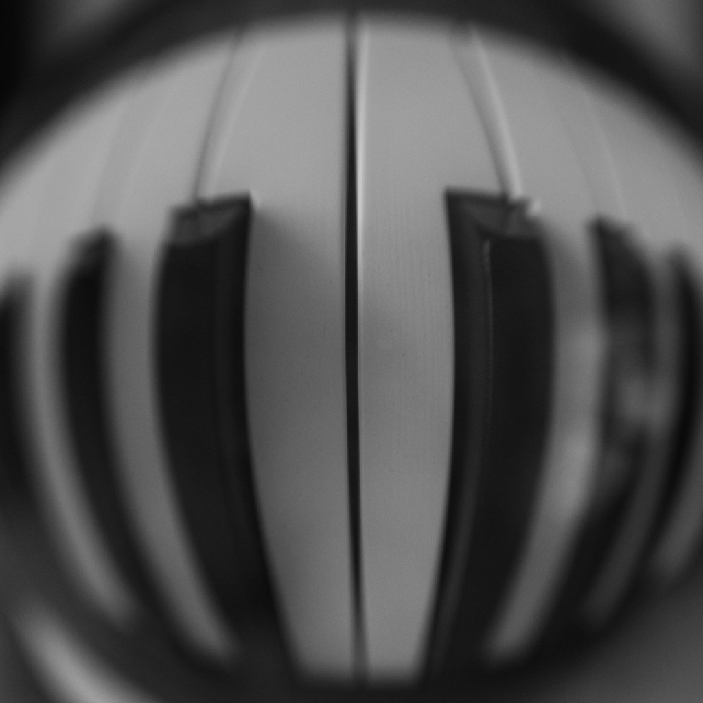 Distorted piano keys, seen through a crystal ball that makes them look curved, with black&white processing. The image is very symmetrical.