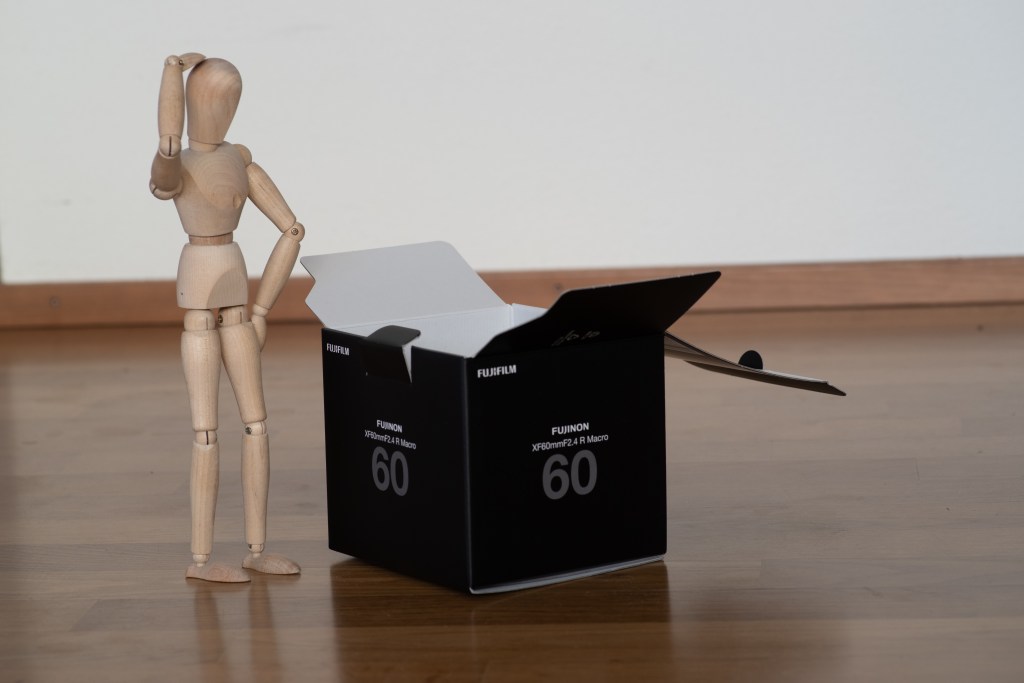 Unedited version of the previous picture of a puzzled manikin in front of a black box. The crop and angle are a bit different, and the black box shows Fujifilm brand and information.