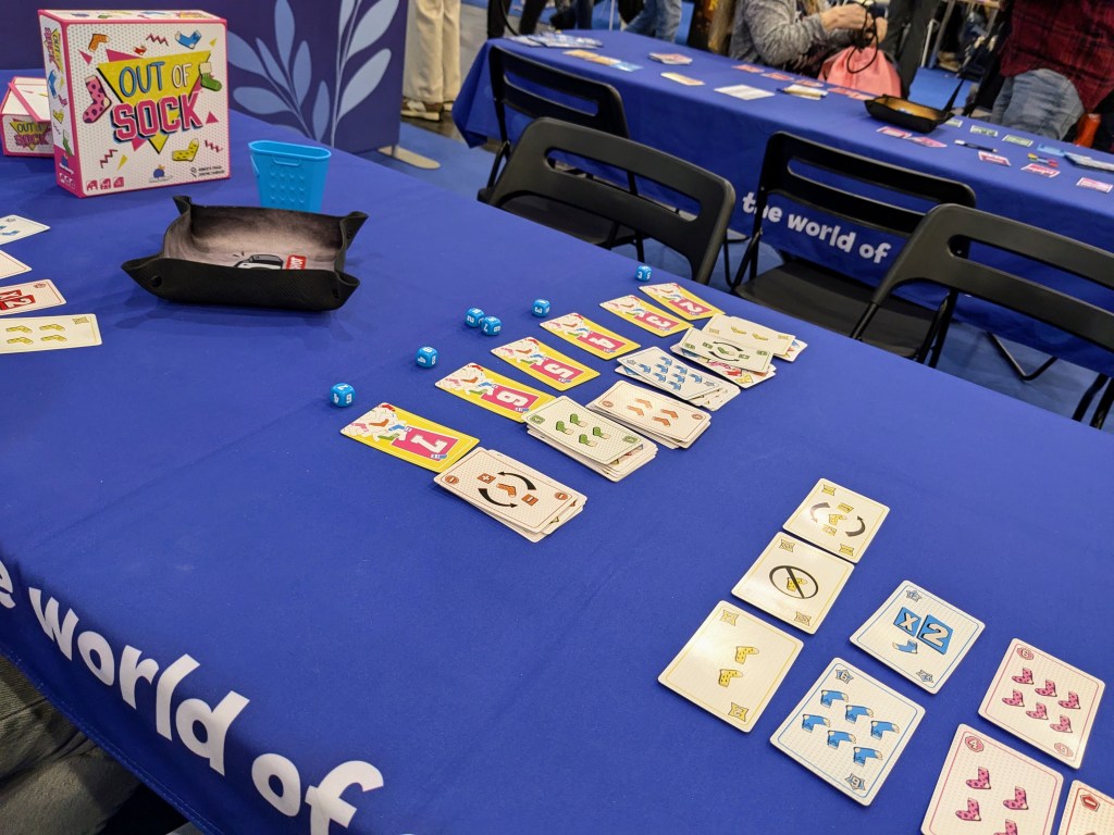 Out of Sock: cards with colorful socks, blue dice and a blue dice holder in the shape of a laundry basket
