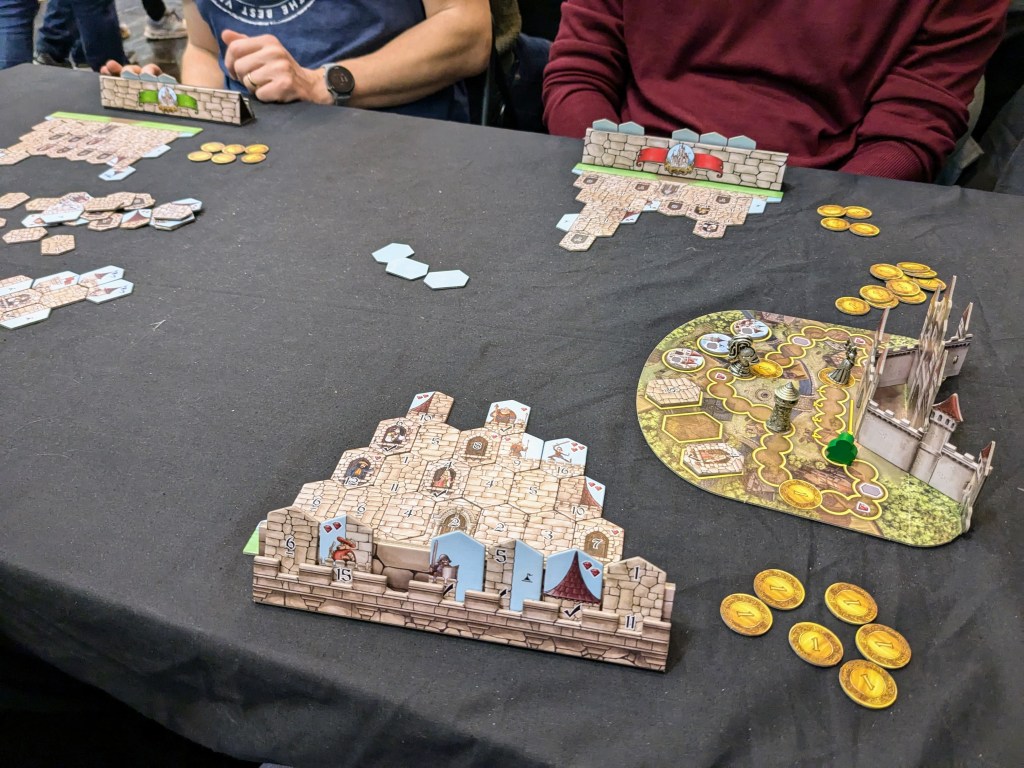 Castle Builder: player boards with of castles built from numbered tiles, scoring board, and gold tokens