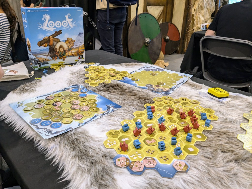 Looot: a map with hex tiles with a bunch of red and blue meeples on it, and a player board with hex tiles placed on them