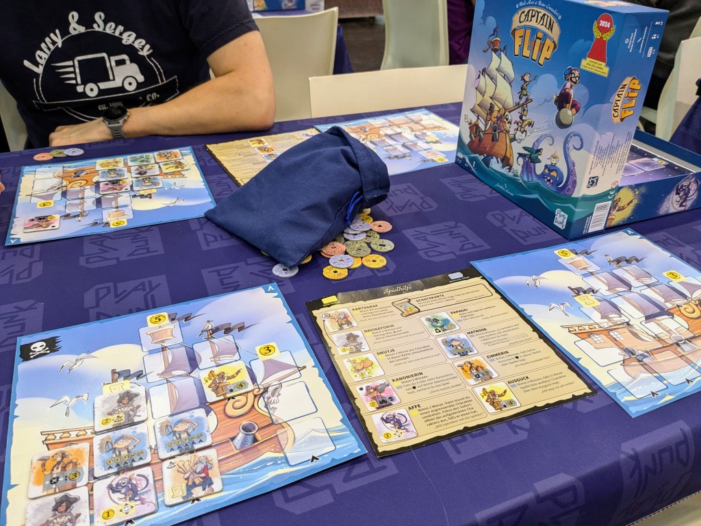 Captain Flip: player boards with a ship and shipmate tiles, a pile of gold tokens and a blue bag of tiles