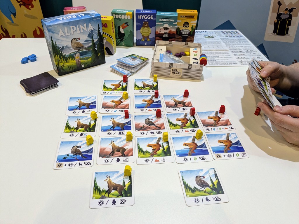 Alpina: a 4×4 grid of cards with animals (birds, frogs, goats) with meeples on some of them