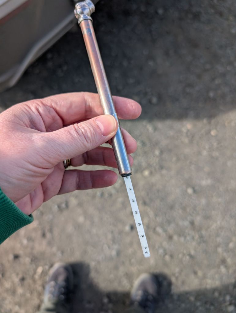 A metallic tube with a small round end and a plastic looking ruler with PSI graduations sticking out of it