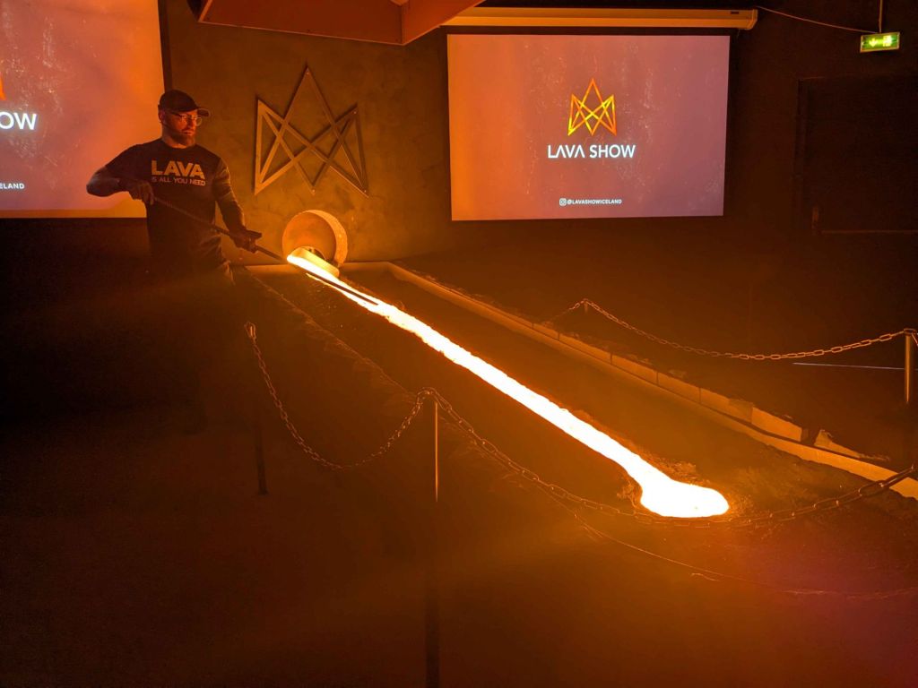 A dark room with a very bright liquid light in the middle and a man standing next to lava