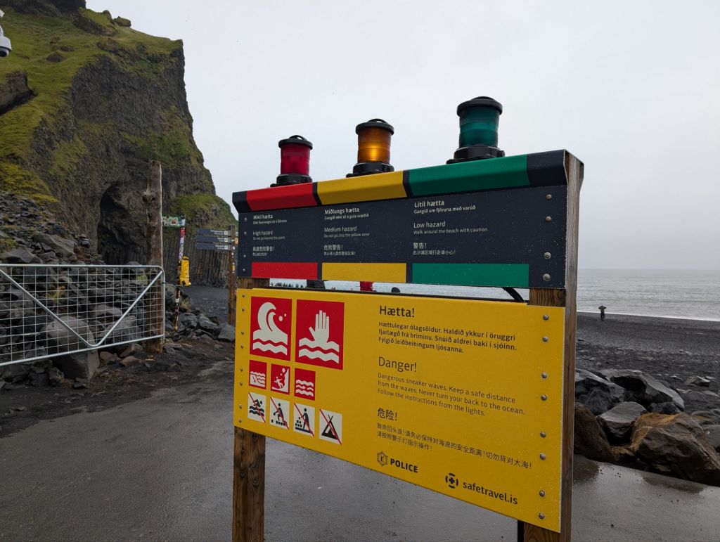 A display with three lights of three colors (red, yellow, green) on top, and indications on whether the beach is safe. The yellow light is lit, meaning that one should stay within a specific area of the beach.