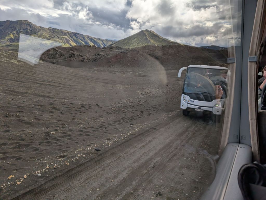 View from a bus window. Crossing another bus, on a narrow road that has no paving and no gravel - a track, really.