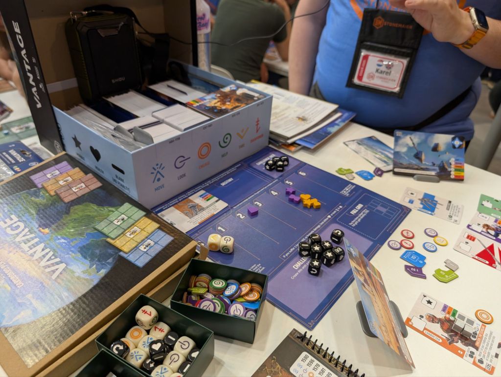 A large box containing a very (very) large number of cards, behind a player mat with dice and tokens.